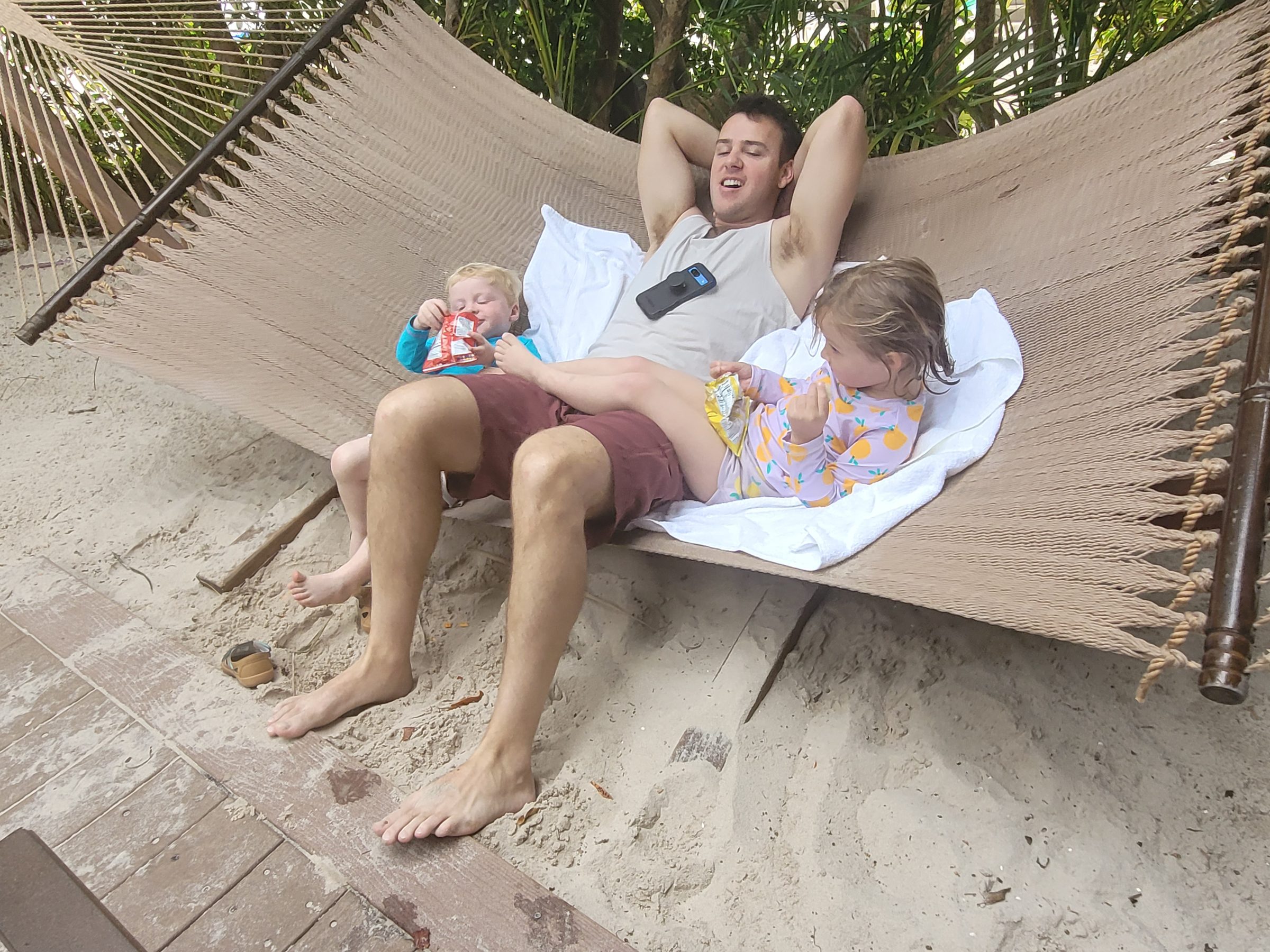 Jim laughing in a hammock with Rabbit and Raccoon at Discovery Cove